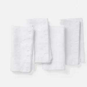 Coyuchi Olivos Embroidered Linen napkin set of four in white, folded on light background.