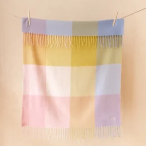 Lambswool Baby Blanket in Pink Block Check by TBCo hanging on a line with fringed edges in portrait view