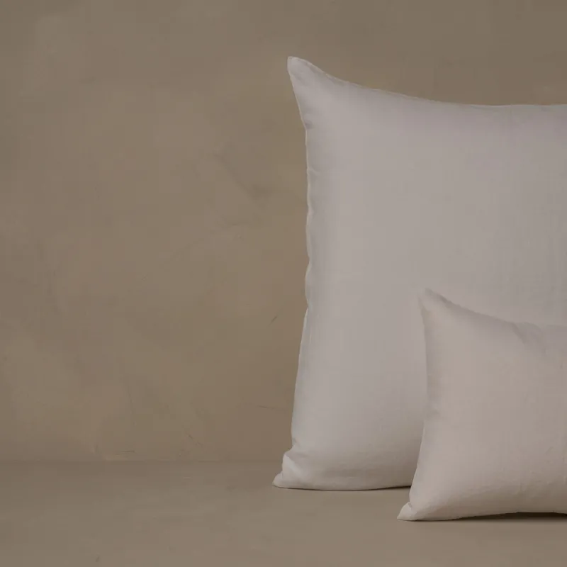 A small boudoir or travel size pillow stacked in front of a large euro size pillow. The pillow cases are made in Italy of breathable and relaxed 100% linen, LETTO Classic Linen in color white.