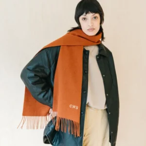 Rust melange TBCo lambswool scarf with fringe styled on model with dark jacket and cream trousers against neutral backdrop