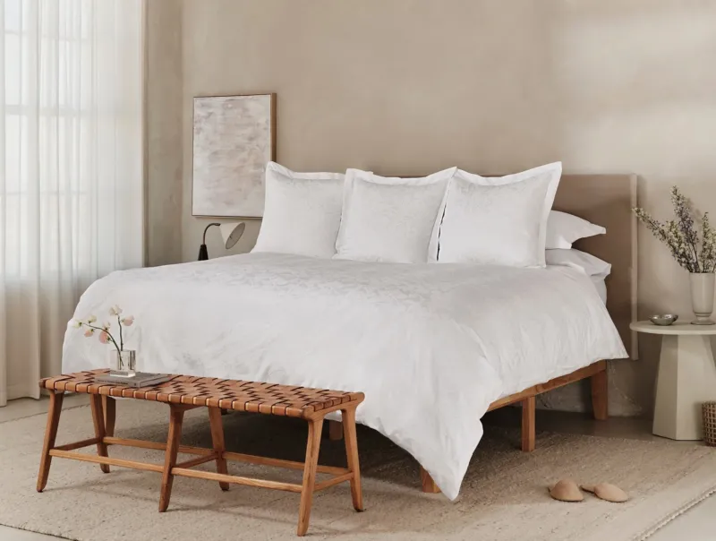 Coyuchi Heritage Percale Jacquard duvet cover styled on a bed in a warm neutral bedroom.