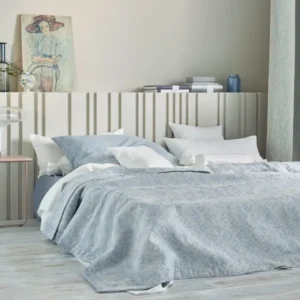 Leitner Valdera tailored bedskirt panels in pale blue on a styled bed.