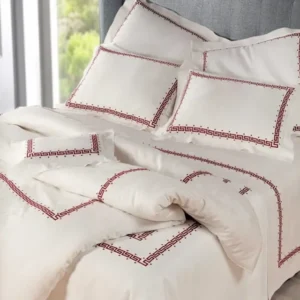 Dea Etruria ivory duvet cover with red Greek key embroidered border on made bed.