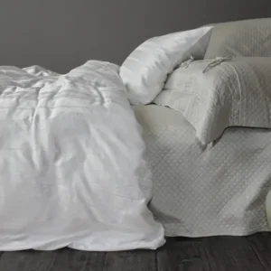 Legna Lucca Stripe decorative pillow styled on bed with white duvet and taupe quilted coverlet.