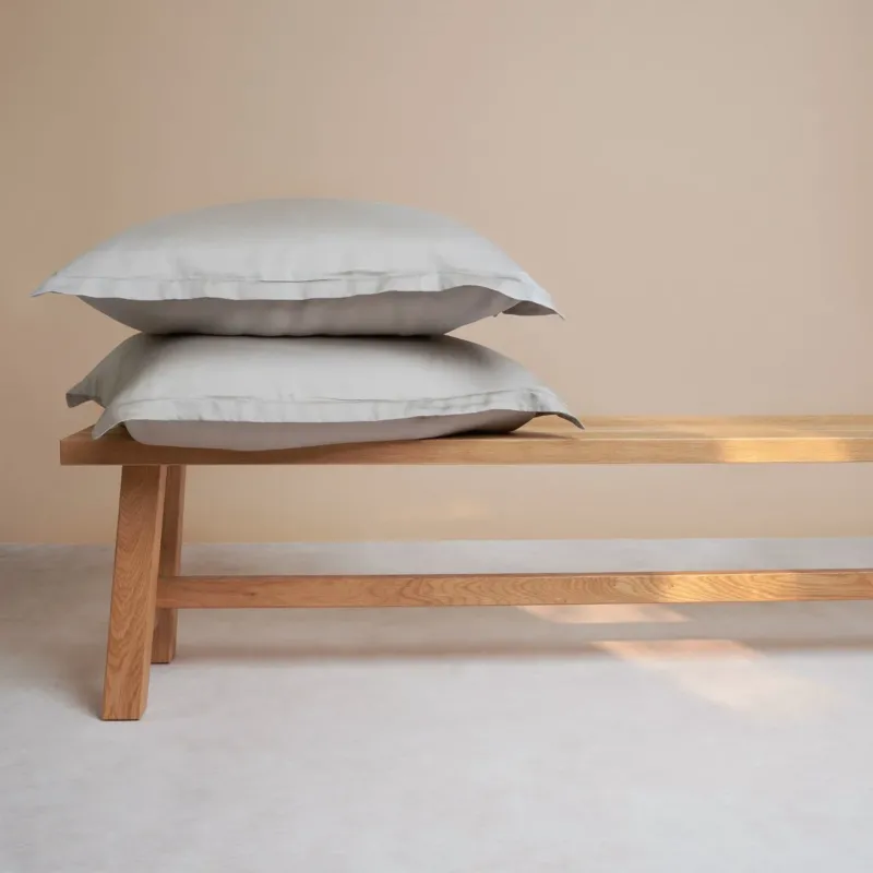 Tencel™ Sateen Pillowcases in Taupe, stacked on a wooden bench